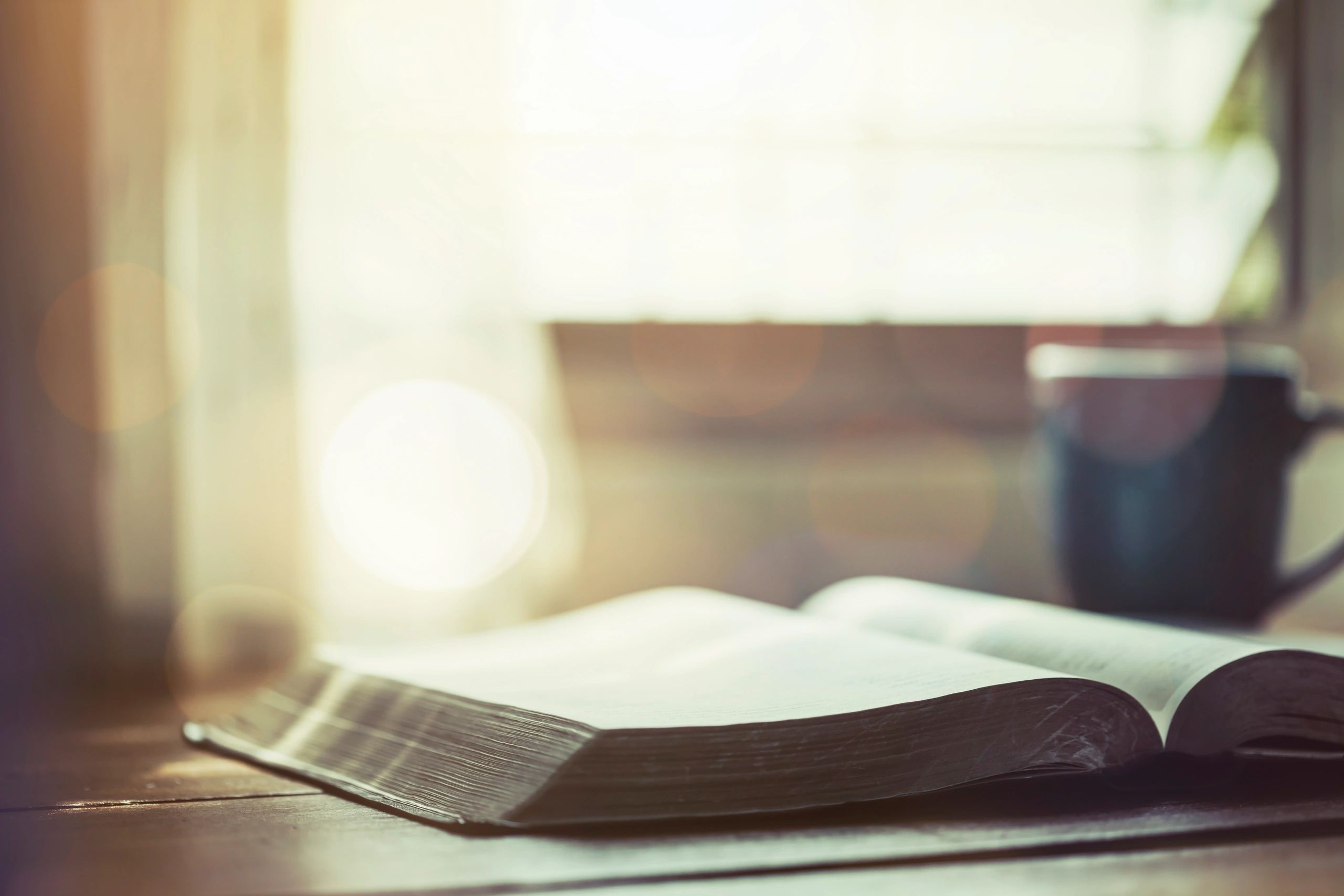 Open Bible and coffee on a wooden table